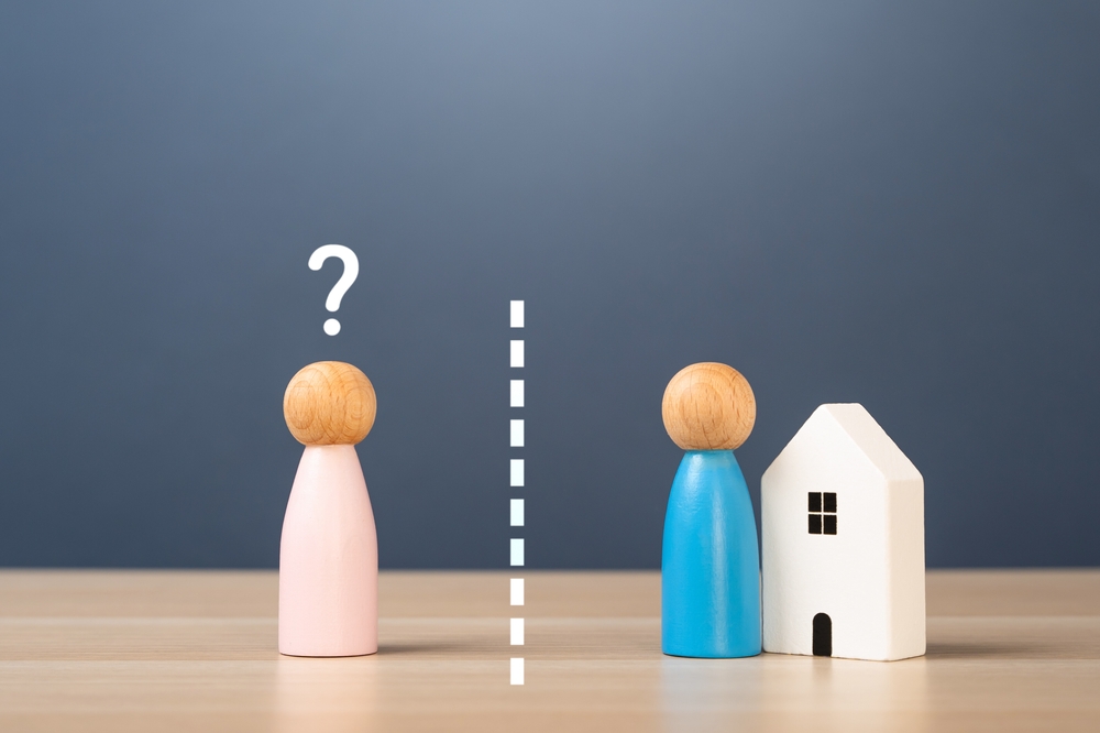 Two toy people separate by a white line with a toy house at the right side